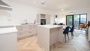 A modern kitchen with a central island, white cabinetry, and a herringbone floor pattern.