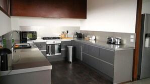 A modern kitchen with stainless steel appliances, a built-in oven, and a coffee maker. - CONTEMPORARY VILLA 350 m2 SEA VIEW SWIMMING POOL (Nice)