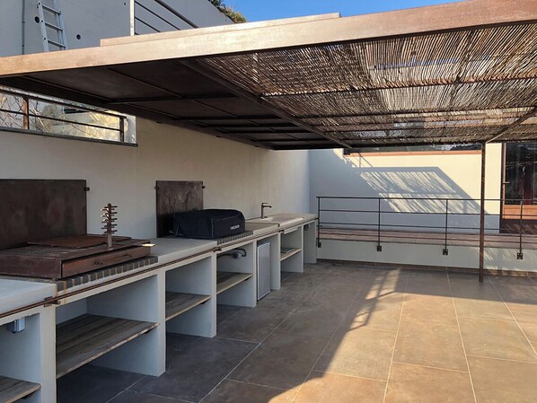 A modern outdoor kitchen area with a built-in grill, a sink, and a dining table.