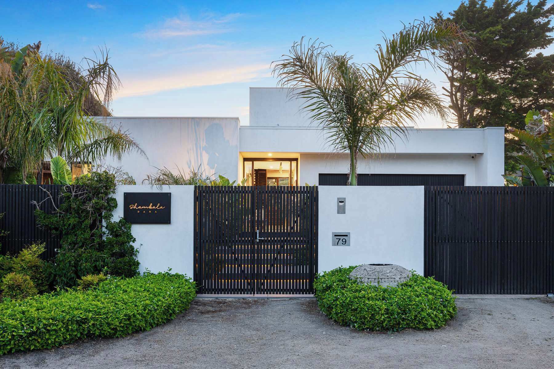 A modern house with a black gate, a sign reading "Shankala DANA", and a number "79" on the wall.
