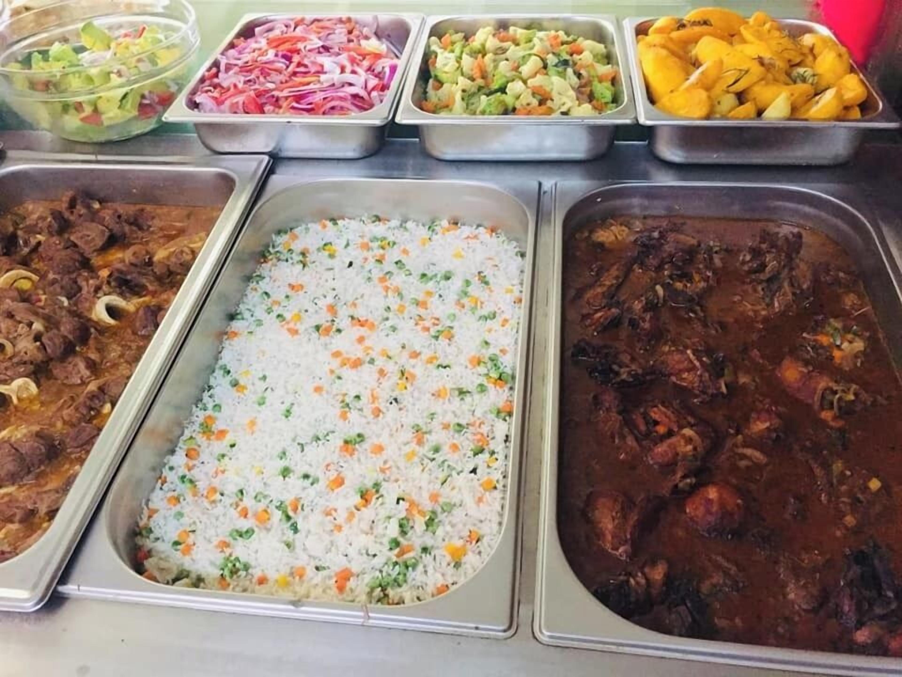 Ein Buffet mit verschiedenen Speisen, darunter Reis, Fleisch und Salate.
