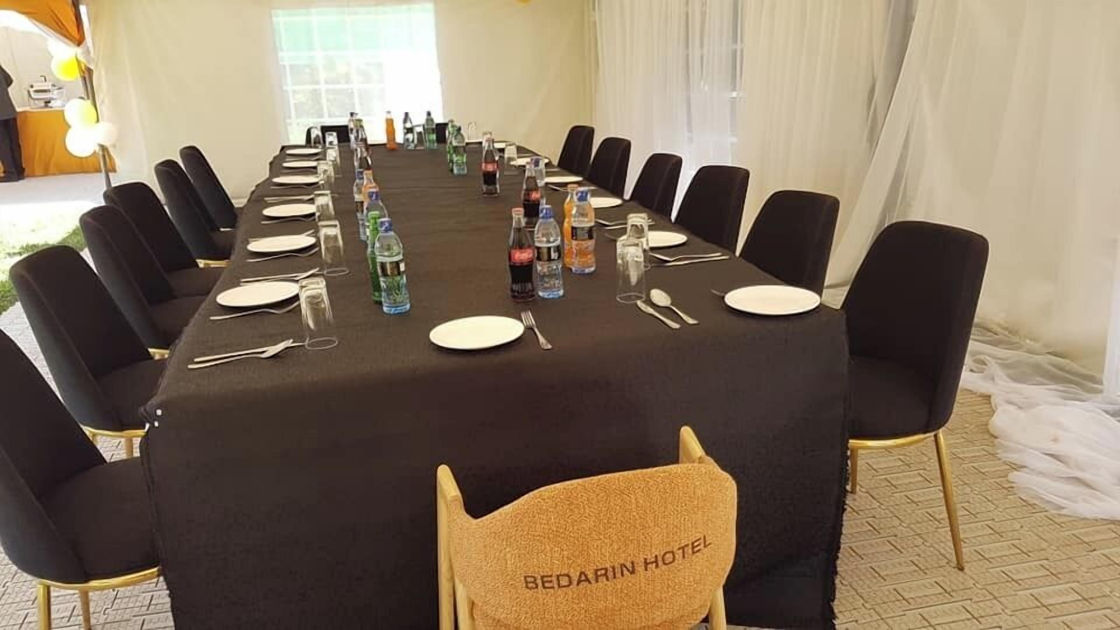 A conference room with a long table set for a meeting, equipped with water bottles, glasses, and cutlery.