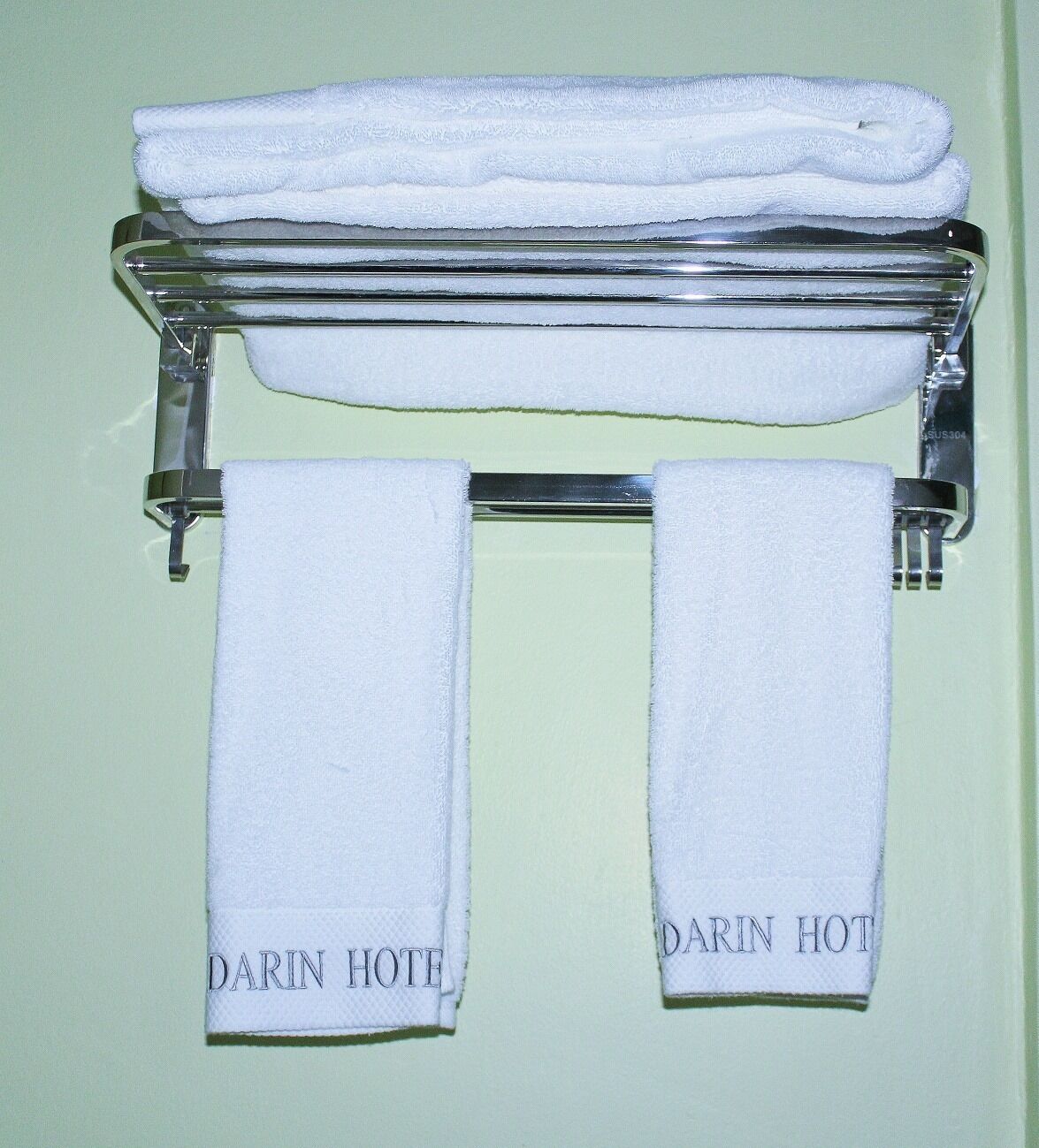 A towel rack with two folded white towels and two towels hanging below, each labeled 'DARIN HOTEL'.
