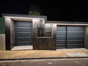Una entrada protegida por una puerta con un letrero que dice 'BELLA VISTA' y dos puertas de garaje cerradas.