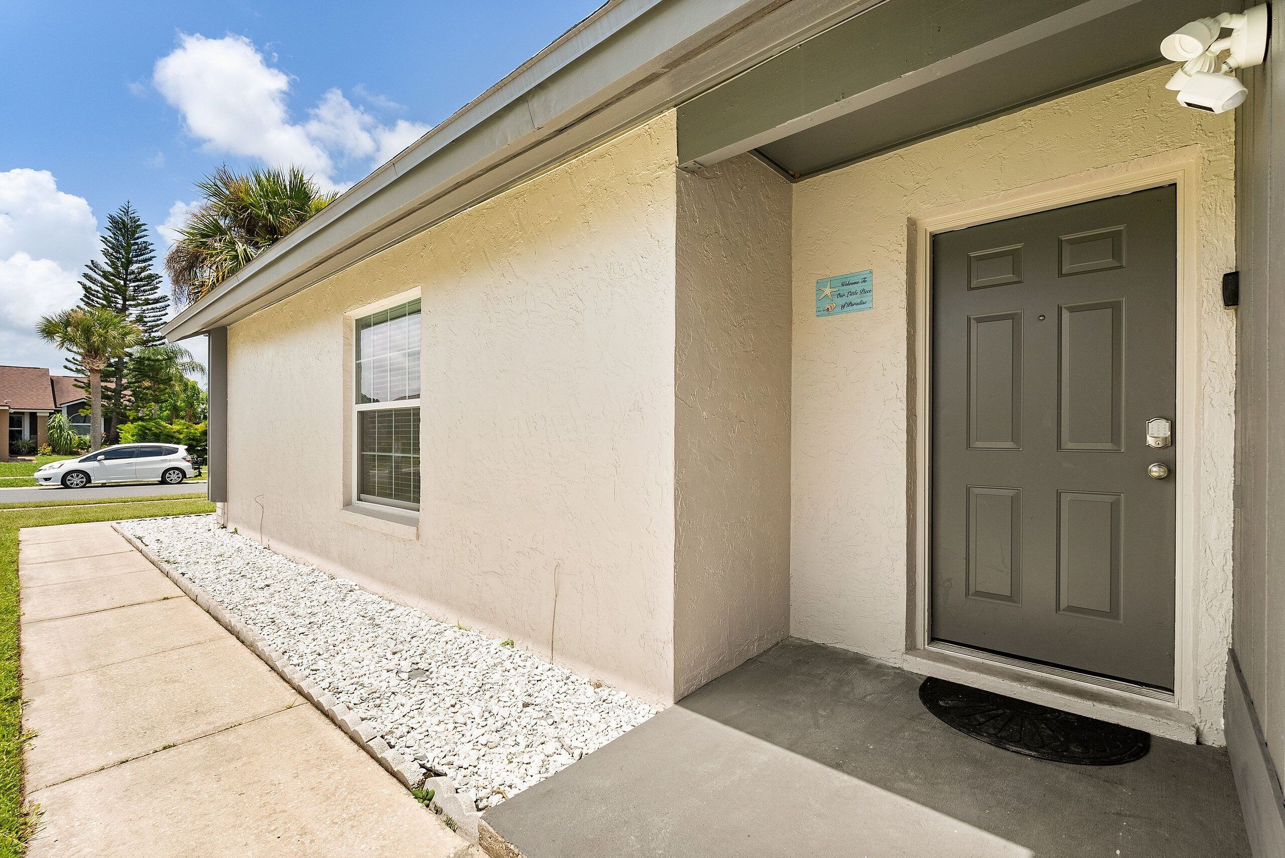 A building with a gray door, a small window, and a sign on the wall.