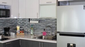 Una cocina moderna con un refrigerador de acero inoxidable, un microondas y un lavamanos con salpicadero de azulejos.
