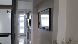 Un pasillo con un refrigerador, una planta en maceta y un espejo en la pared.