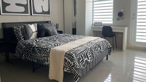 Un dormitorio con cama, escritorio y silla. Hay dos cuadros abstractos grandes en la pared.