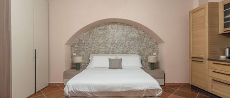 A bedroom with a large bed, wooden headboard, nightstands, and a wooden wardrobe.