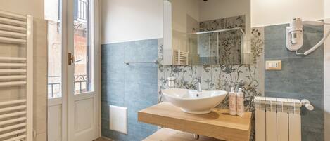 Une salle de bain moderne avec un grand miroir, un lavabo sur colonne et un porte-serviettes.