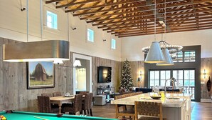 A spacious indoor area with a pool table, wooden ceiling beams, and a dining area with chairs and a table. - Luxury Barn Retreat, Mountain Views and Creekside Calm (Ellijay)