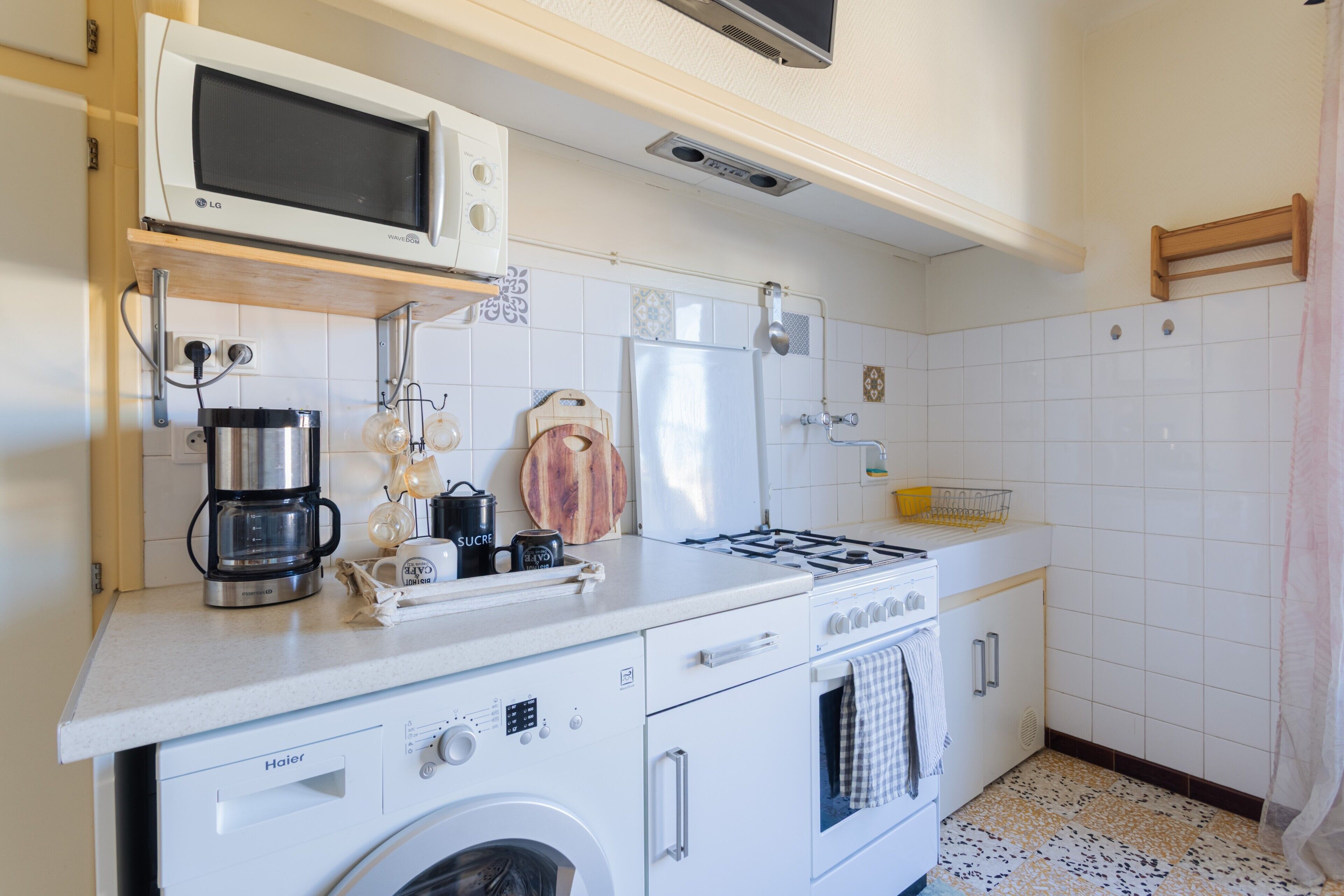 A compact kitchen with a microwave, coffee maker, and a stove.