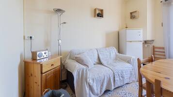 Ein kleiner, gemütlicher Raum mit einem Bett, einer Holzkommode, einem Tisch und einem Kühlschrank.