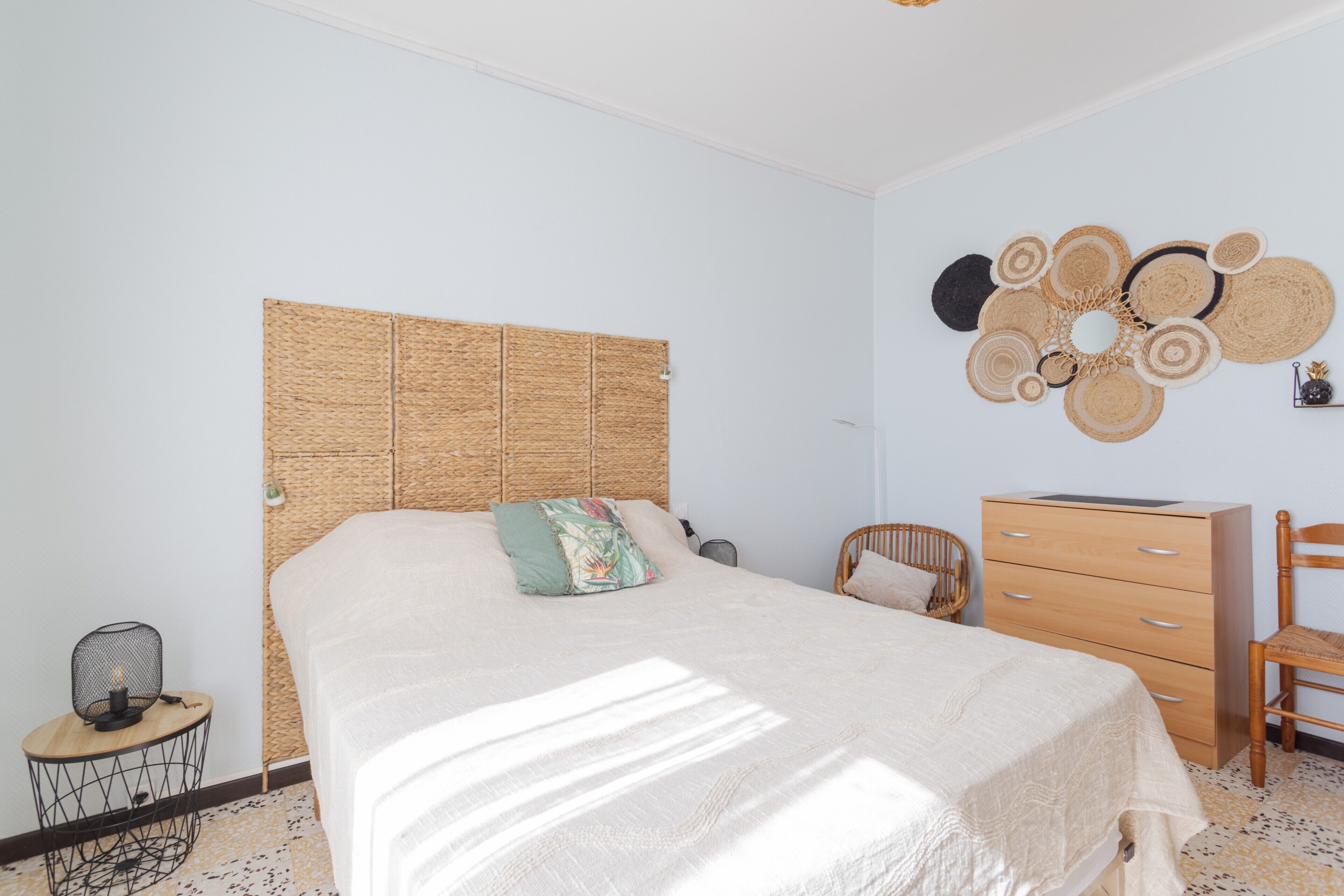 Ein Schlafzimmer mit einem Bett, einem Schminktisch, einem Sessel und einer Wanddekoration.