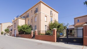 Un immeuble résidentiel à plusieurs étages, doté de balcons, d’une entrée sécurisée et surplombant un ciel dégagé.