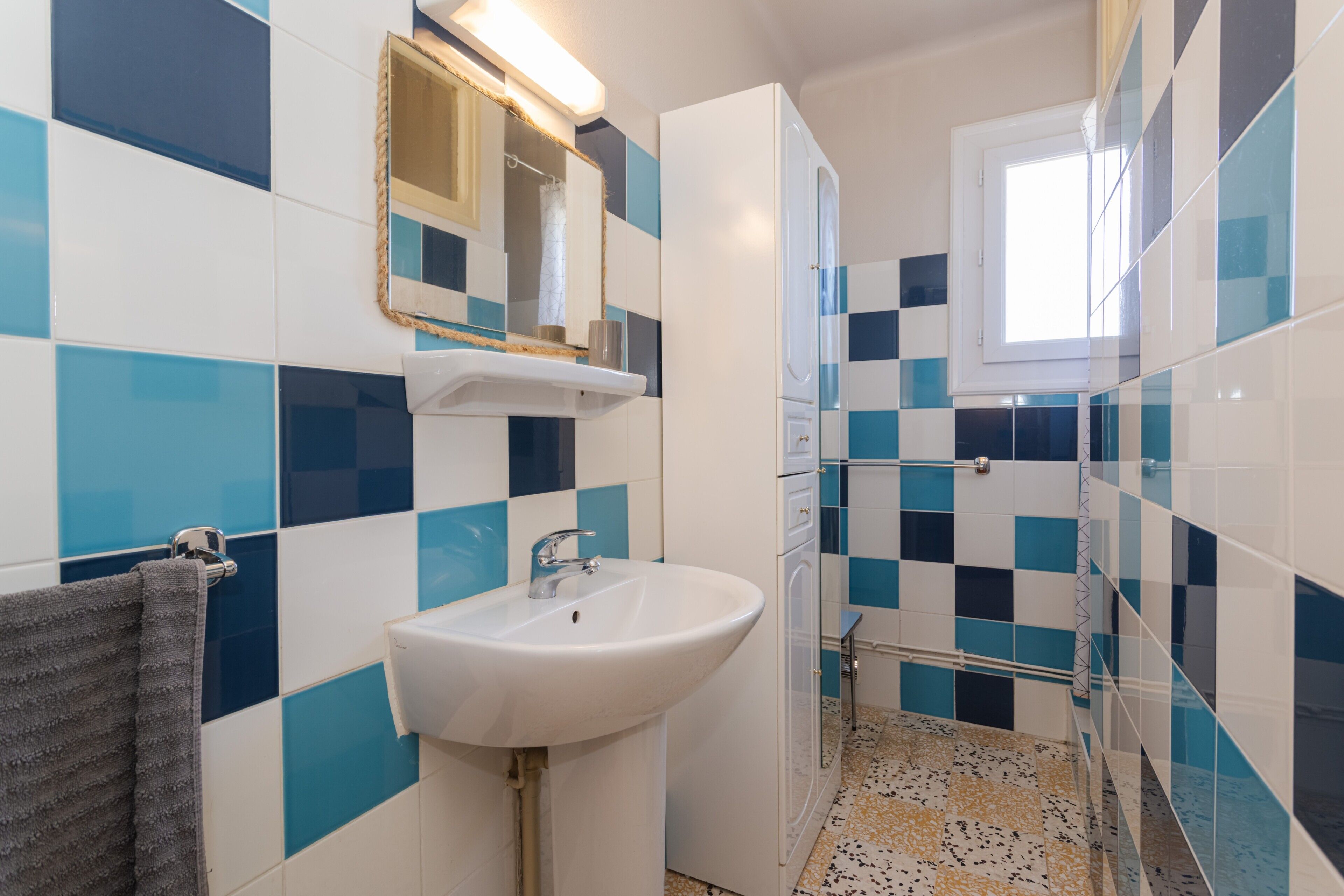 Un baño con lavamanos blanco, un espejo y zona de ducha.