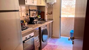 Une cuisine compacte équipée d’un lave-linge, d’un four encastré et d’un évier.
