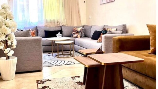 Un salon moderne avec un canapé gris, un fauteuil marron et une table basse.