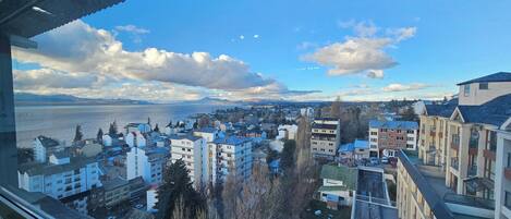 A cityscape with residential buildings, a body of water, and mountains in the distance.