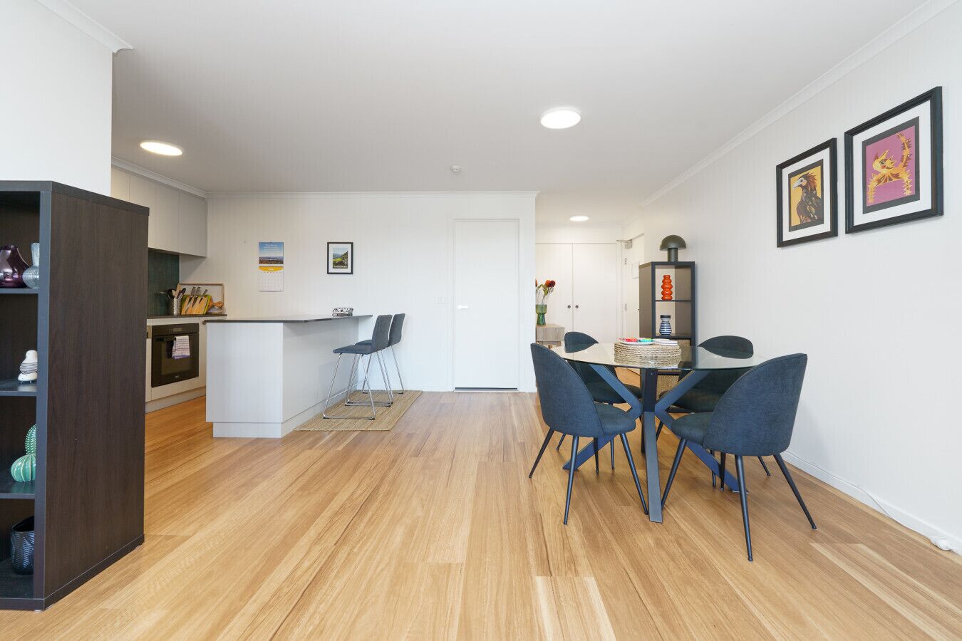 A modern kitchen with a dining area, wooden flooring, and a small bar area.