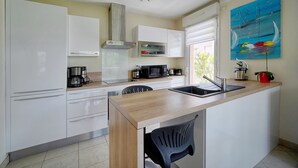Una cocina moderna con armarios blancos, encimera de madera, un lavabo, un microondas y una cafetera.