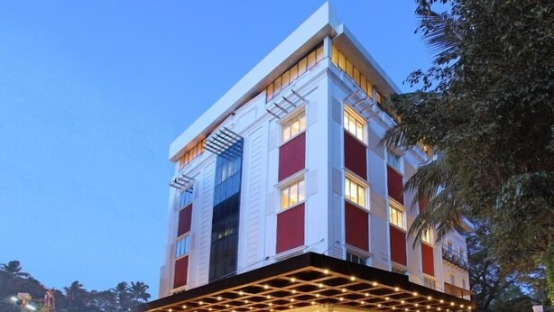 A multi-story hotel with a covered entrance and a car parked in front. - Hotel National Park  (Kottayam)