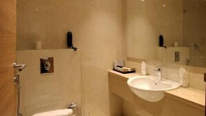 A modern bathroom with a toilet, bidet, sink, and mirror. - Hotel National Park  (Kottayam)