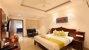 A hotel room with a large bed, a desk with a telephone, a chair, and a television. - Hotel National Park  (Kottayam)