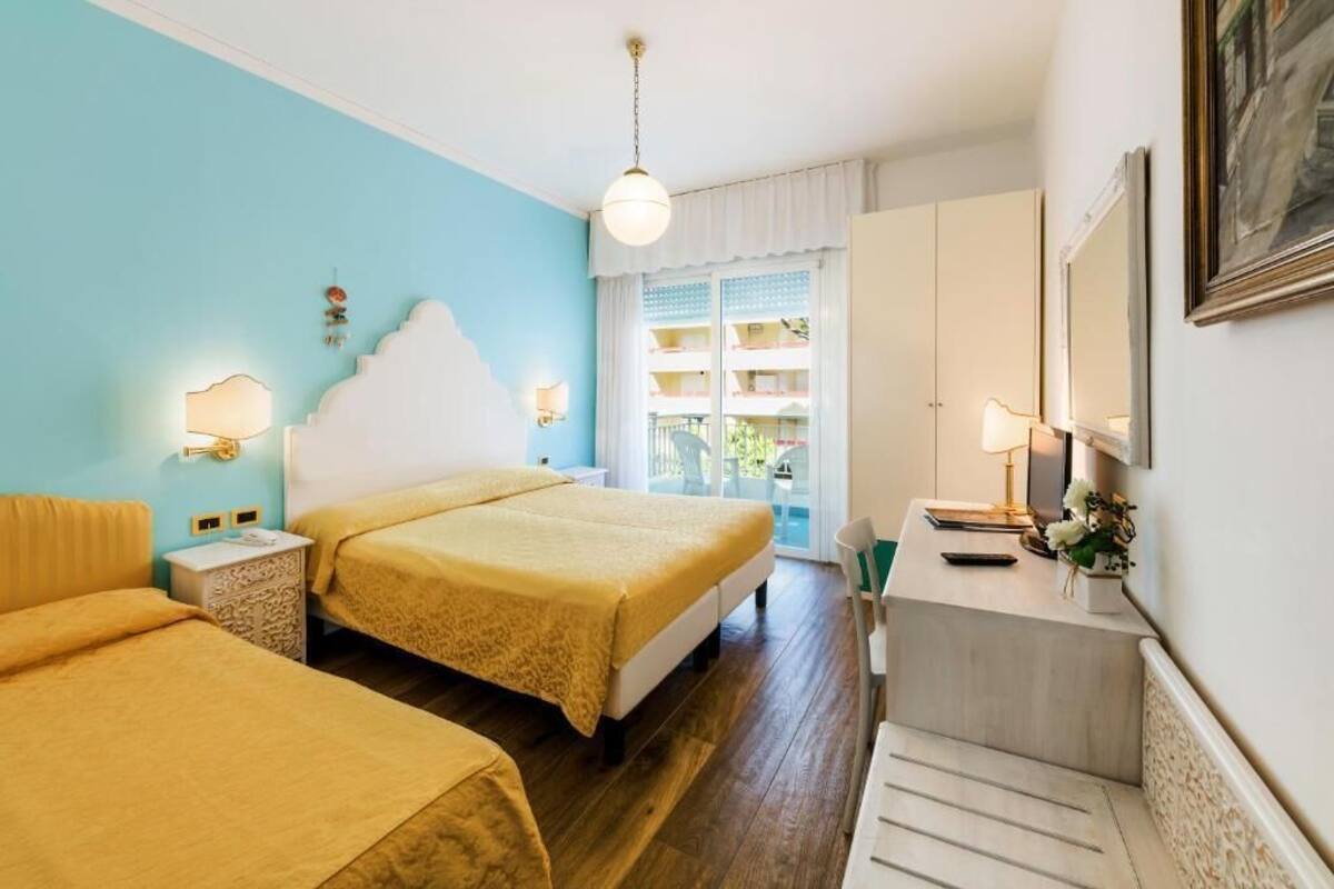 Ein Hotelzimmer mit zwei Betten, einem Schreibtisch und einem Balkon mit Blick.