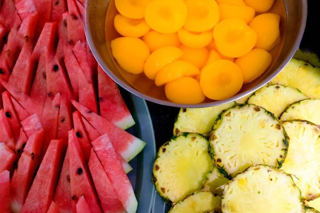 Un saladier rempli de fruits coupés en tranches, notamment de la pastèque et des abricots.