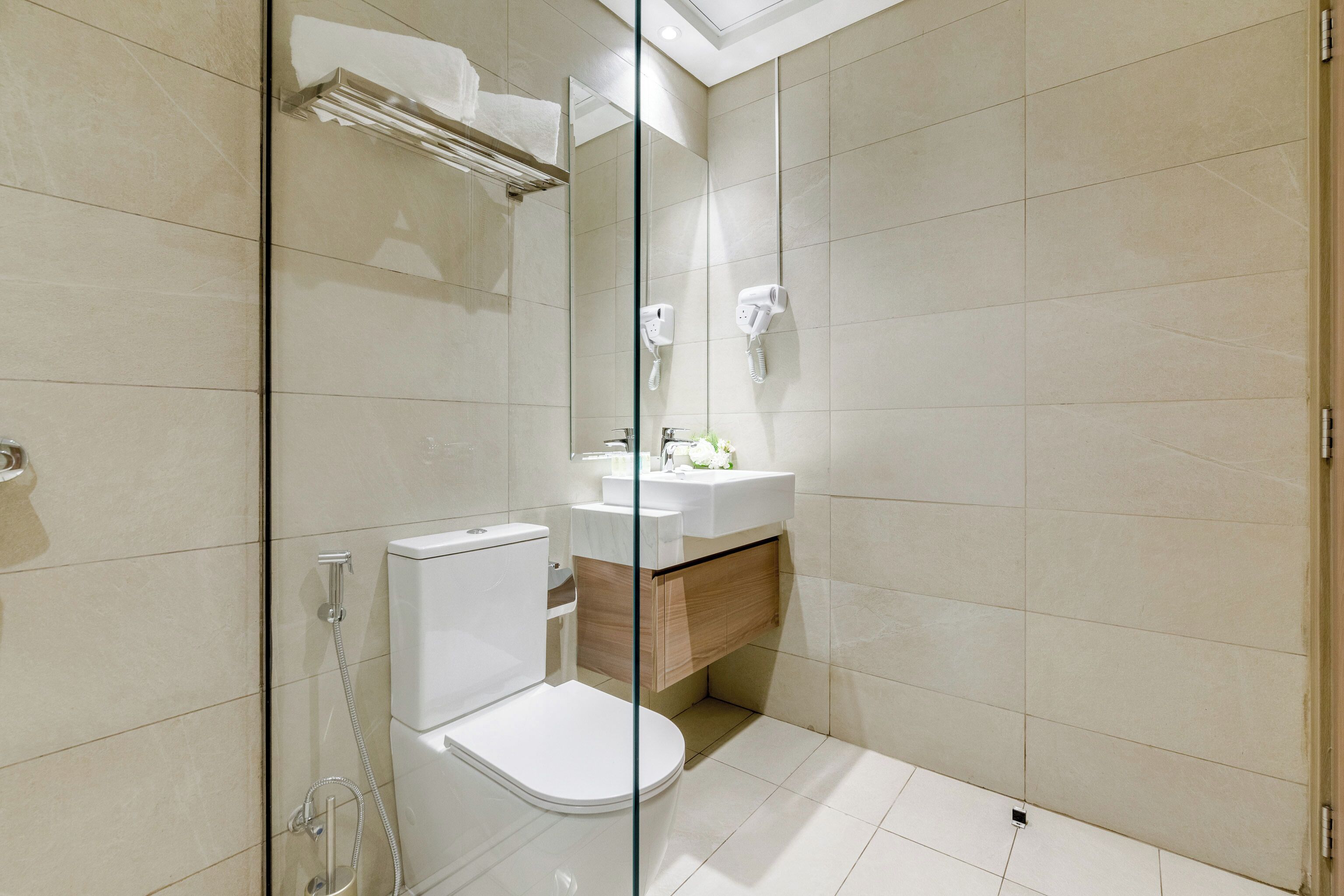A modern bathroom with a glass shower enclosure, a toilet, and a vanity with a mirror.