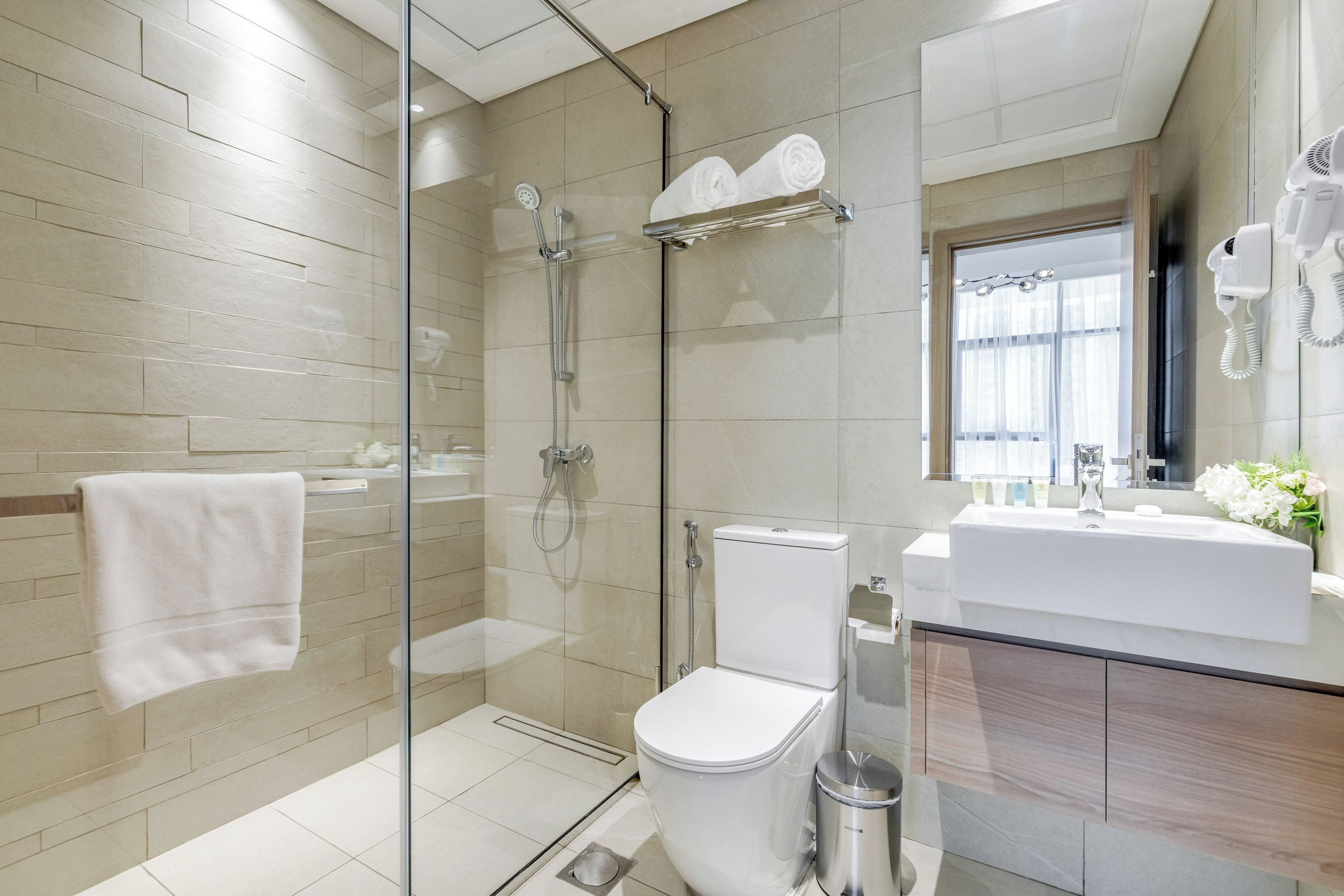 A modern bathroom with a glass-enclosed shower, a white toilet, a sink with a mirror, and a towel rack.