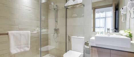A modern bathroom with a glass-enclosed shower, a white toilet, a sink with a mirror, and a towel rack.