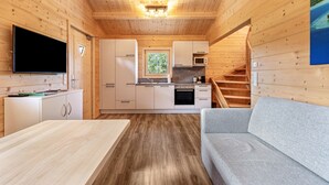 Ein Holzblockhaus im Inneren mit Küche, Essbereich und einer Couch.