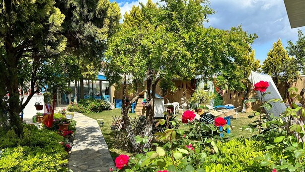 A garden with a stone pathway, various plants, and a wooden structure. - Bonjourla Otel (Urla)