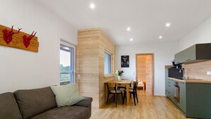 A modern interior with a sofa, dining table, and kitchen area. - Apartment 'Morning Sun' with Shared Garden and Wi-Fi (Donaueschingen)