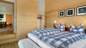 A bedroom with wooden panel walls, a bed with checkered bedding, a white rug, and a wooden headboard. - Apartment 'Morning Sun' with Shared Garden and Wi-Fi (Donaueschingen)
