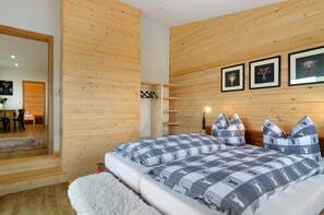 A bedroom with wooden panel walls, a bed with checkered bedding, a white rug, and a wooden headboard. - Apartment 'Morning Sun' with Shared Garden and Wi-Fi (Donaueschingen)