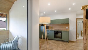 A modern kitchen with green cabinets, a wooden floor, and a floor lamp. - Holiday Apartment 'Sternenhimmel' with Shared Garden, Balcony and Wi-Fi (Donaueschingen)
