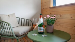 A green metal chair, two wine glasses, a bottle of wine, and a potted plant with pink flowers on a round table. - Holiday Apartment 'Sternenhimmel' with Shared Garden, Balcony and Wi-Fi (Donaueschingen)