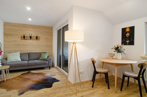 A modern living room with a sofa, a round table, chairs, a lamp, and a cowhide rug.