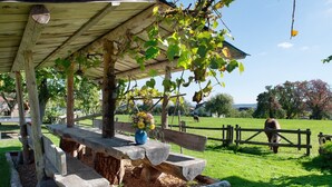 A wooden pergola with a bench and a vase of flowers, surrounded by a grassy area and a wooden fence. - Holiday Apartment 'Sternenhimmel' with Shared Garden, Balcony and Wi-Fi (Donaueschingen)