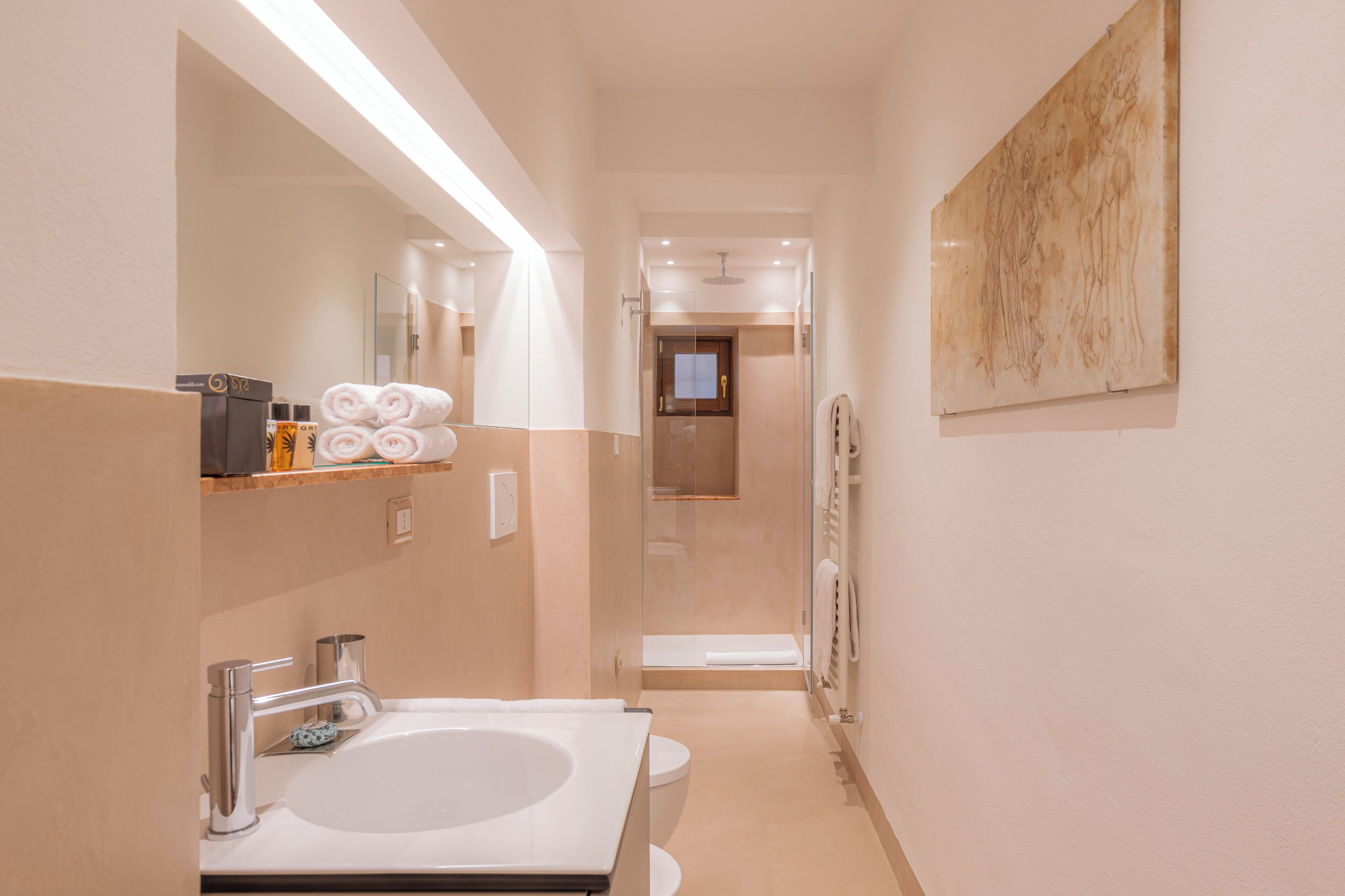 A modern bathroom with a large sink, a glass shower enclosure, and a towel rack.