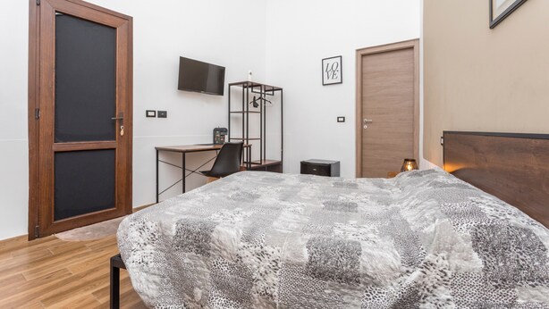 A bedroom with a bed, a desk, a chair, a TV, and a wardrobe. - Room 'Balestrate' with Balcony, Wi-Fi and Air Conditioning (Acireale)