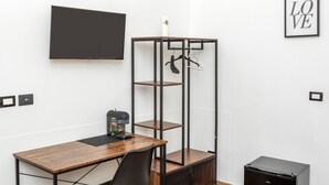 A room with a wooden desk, a black coffee machine, a black storage unit with shelves, a black TV on the wall, and a framed 'LOVE' sign. - Room 'Balestrate' with Balcony, Wi-Fi and Air Conditioning (Acireale)