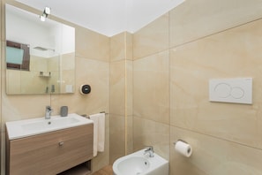 A modern bathroom with a sink, mirror, and toilet.