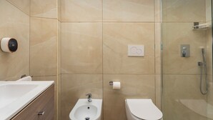 Een moderne badkamer met een toilet, douchecabine en bidet.