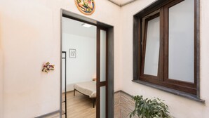 Een kamer met een bed, een raam en een deur die naar een andere kamer leidt.