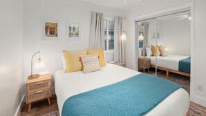A modern bedroom with a large bed, bedside tables, a mirror, and artwork on the walls.