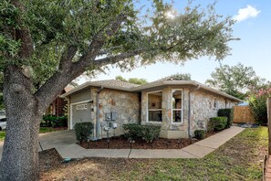 A single-story house with a stone facade, a garage, and a large tree in the front yard. - Cozy North Austin Getaway  Peaceful  Near Domain (Austin)